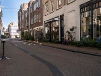 a street with brick buildings and tables and chairs lining the sidewalk that is lined with buildings and a flag