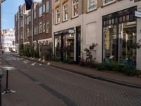 a street with brick buildings and tables and chairs lining the sidewalk that is lined with buildings and a flag