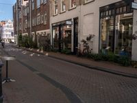 a street with brick buildings and tables and chairs lining the sidewalk that is lined with buildings and a flag