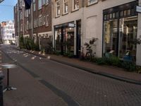 a street with brick buildings and tables and chairs lining the sidewalk that is lined with buildings and a flag