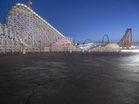 an amusement park at dusk with many rides in the background or empty ground at the same time