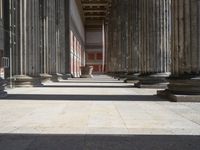 large columns and a stone vase in an open space with windows in the background,