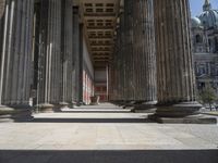 large columns and a stone vase in an open space with windows in the background,