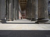 large columns and a stone vase in an open space with windows in the background,