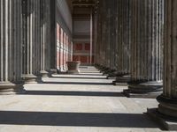 large columns and a stone vase in an open space with windows in the background,