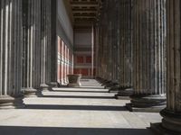 large columns and a stone vase in an open space with windows in the background,