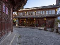 an old chinese looking building on the side of a street in front of a store