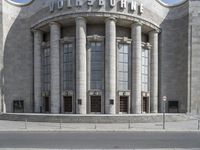 a tall gray building with two large columns that have lettering on it on top of each column