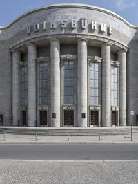 a car is parked at the curb of a building with columns and stairs on either side of it