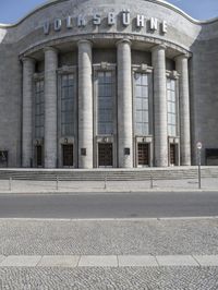 a car is parked at the curb of a building with columns and stairs on either side of it