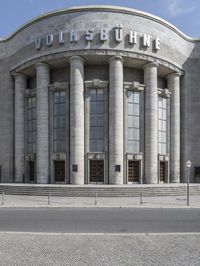 a car is parked at the curb of a building with columns and stairs on either side of it