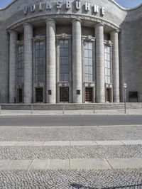 a car is parked at the curb of a building with columns and stairs on either side of it