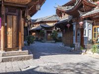 a small paved courtyard with wooden doors and wooden pillars surrounding the area is lined with tall, ornate brick and painted architecture