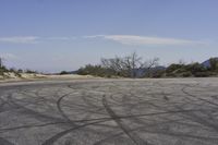 a view along a dirt road of an empty field and mountains in the distance of the scene