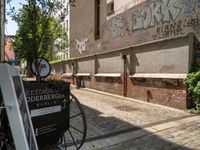 an antique cart on the side of a narrow street near a building and graffiti covered wall