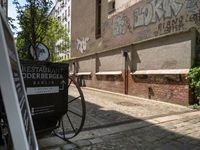 an antique cart on the side of a narrow street near a building and graffiti covered wall