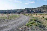 a dirt road going into a valley in the distance, with an open gate on the right