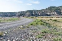 a dirt road going into a valley in the distance, with an open gate on the right