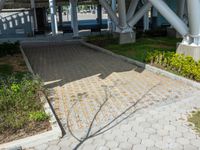 a walkway is surrounded by brick pavers and grass and the shadow is cast on it