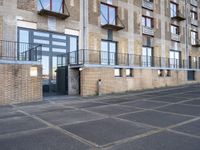 a sidewalk outside of an apartment block with an open door and some windows on it