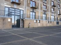 a sidewalk outside of an apartment block with an open door and some windows on it