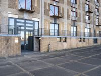 a sidewalk outside of an apartment block with an open door and some windows on it