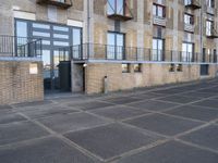 a sidewalk outside of an apartment block with an open door and some windows on it