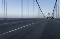 an approaching car on the bridge at dusk with blurry traffic in the background, with cars driving on road