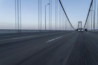 an approaching car on the bridge at dusk with blurry traffic in the background, with cars driving on road