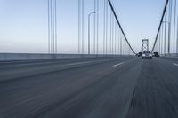 an approaching car on the bridge at dusk with blurry traffic in the background, with cars driving on road