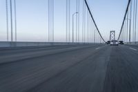 an approaching car on the bridge at dusk with blurry traffic in the background, with cars driving on road