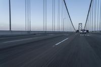 an approaching car on the bridge at dusk with blurry traffic in the background, with cars driving on road