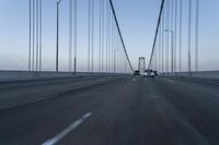 an approaching car on the bridge at dusk with blurry traffic in the background, with cars driving on road