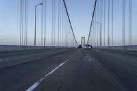 an approaching car on the bridge at dusk with blurry traffic in the background, with cars driving on road