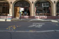 colorful markings line the street outside of a restaurant in a small town with an arched building