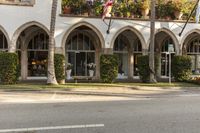 an arched building with planter boxes and flowers on it's windows along the street