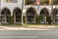 an arched building with planter boxes and flowers on it's windows along the street