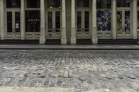the front entrance to an old building with pillars and columns on it on a brick street