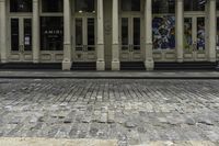 the front entrance to an old building with pillars and columns on it on a brick street