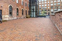 red brick floor with two building in the background from top of a roof and on the ground is a brick wall
