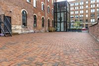 red brick floor with two building in the background from top of a roof and on the ground is a brick wall