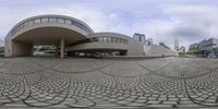 a panoramic view of an architectural building and walkway with circular tiles on it