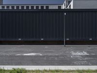 black and white chalk drawings on asphalt in urban setting, near building with dark blue vertical metal gate