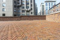 red brick floor with two building in the background from top of a roof and on the ground is a brick wall