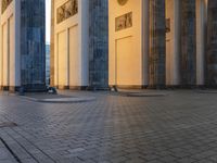 a person sits on top of a stone floor next to a street with pillars in the background