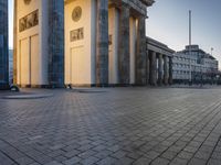 a person sits on top of a stone floor next to a street with pillars in the background