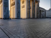 a person sits on top of a stone floor next to a street with pillars in the background