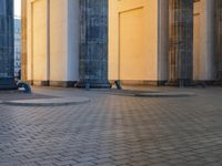 a person sits on top of a stone floor next to a street with pillars in the background