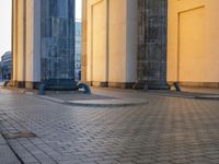 a person sits on top of a stone floor next to a street with pillars in the background