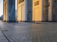 a person sits on top of a stone floor next to a street with pillars in the background